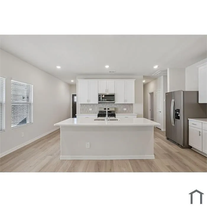 Open-concept kitchen with a large island, white shaker cabinetry, stainless steel appliances, and wood-finish flooring