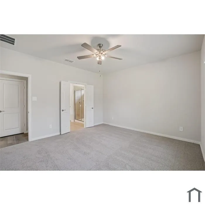 Spacious room featuring light gray carpet, neutral wall paint, and a ceiling fan with integrated lighting