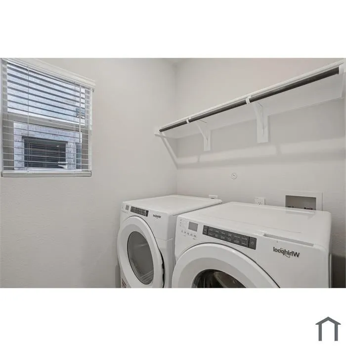 White walls, window with blinds, upper storage shelf, and a clothing rod