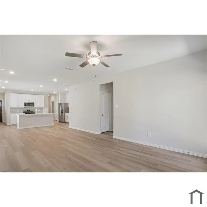 Open-concept living space with wood-finish flooring, recessed lighting, and a ceiling fan