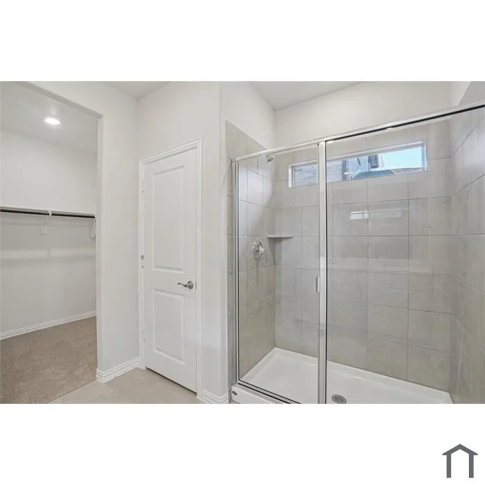 Shower enclosure with glass sliding door and tile surround, featuring a built-in shelf
