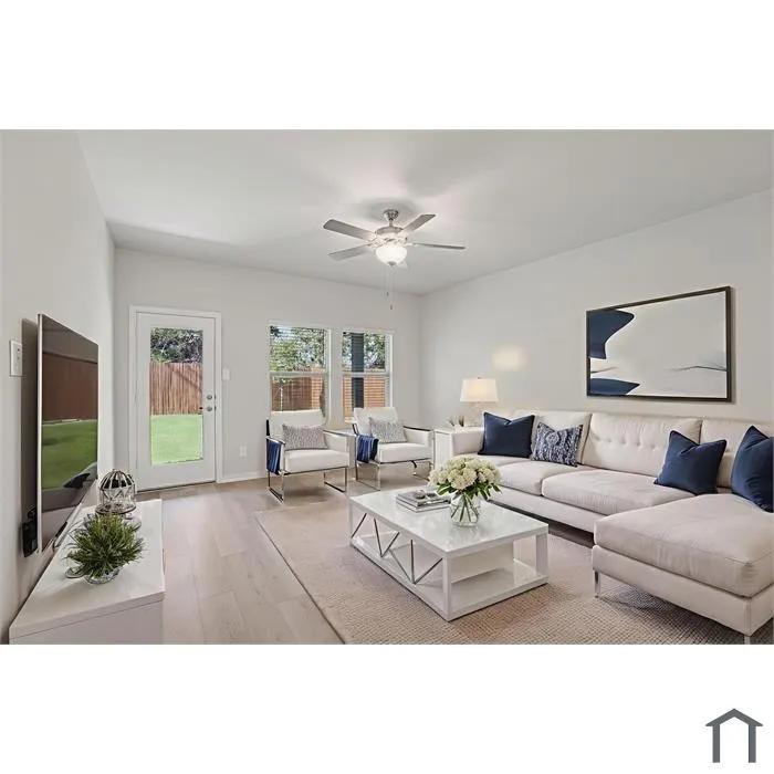Spacious living area featuring wood-finish flooring, a ceiling fan with integrated lighting, and white walls