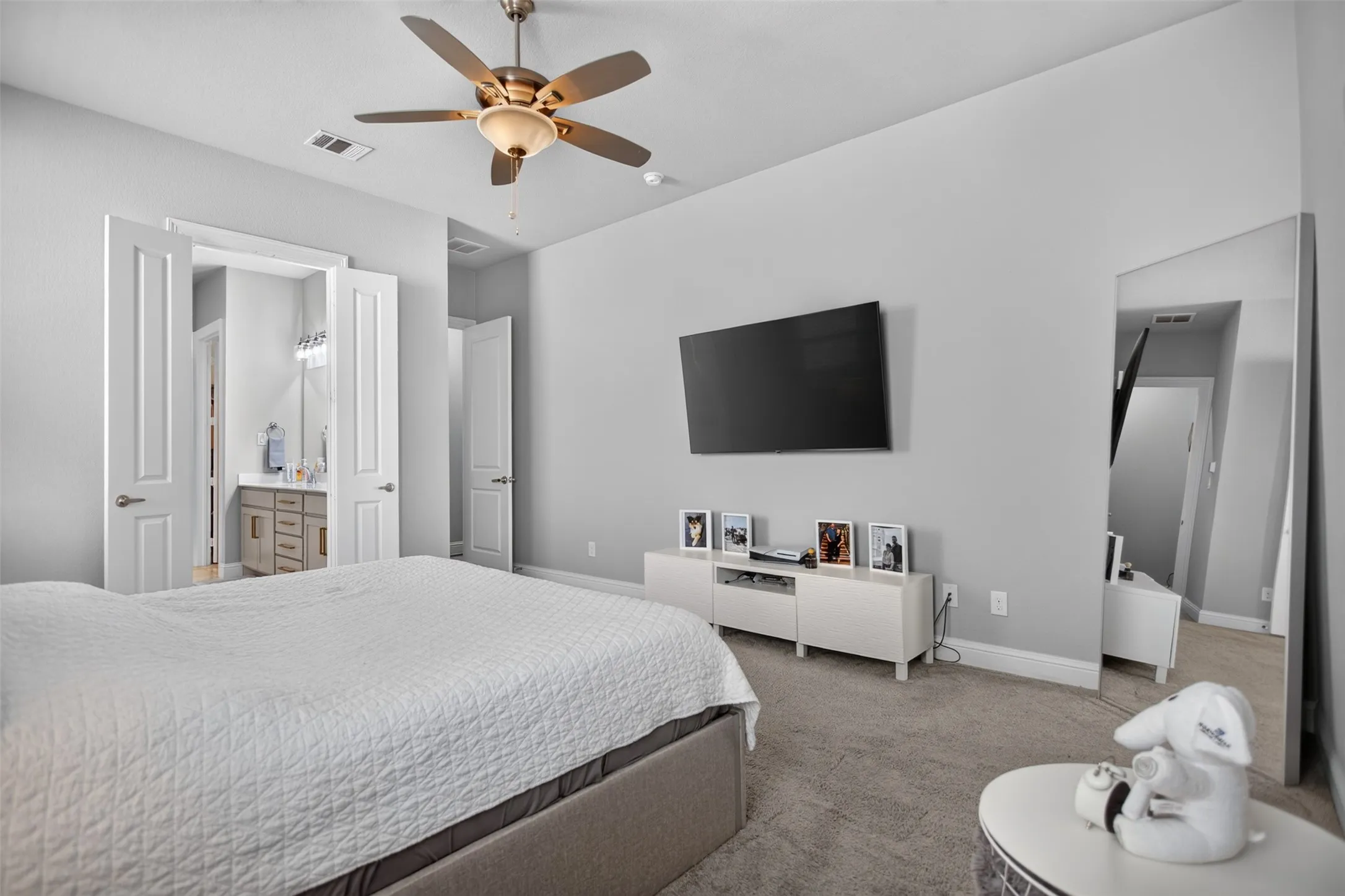 Carpeted room with a ceiling fan, recessed lighting, and a wall-mounted display