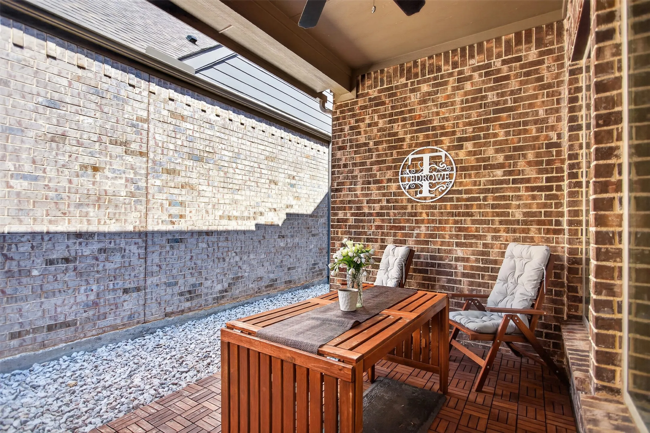 Covered patio with brick wall and wood-finish tile flooring