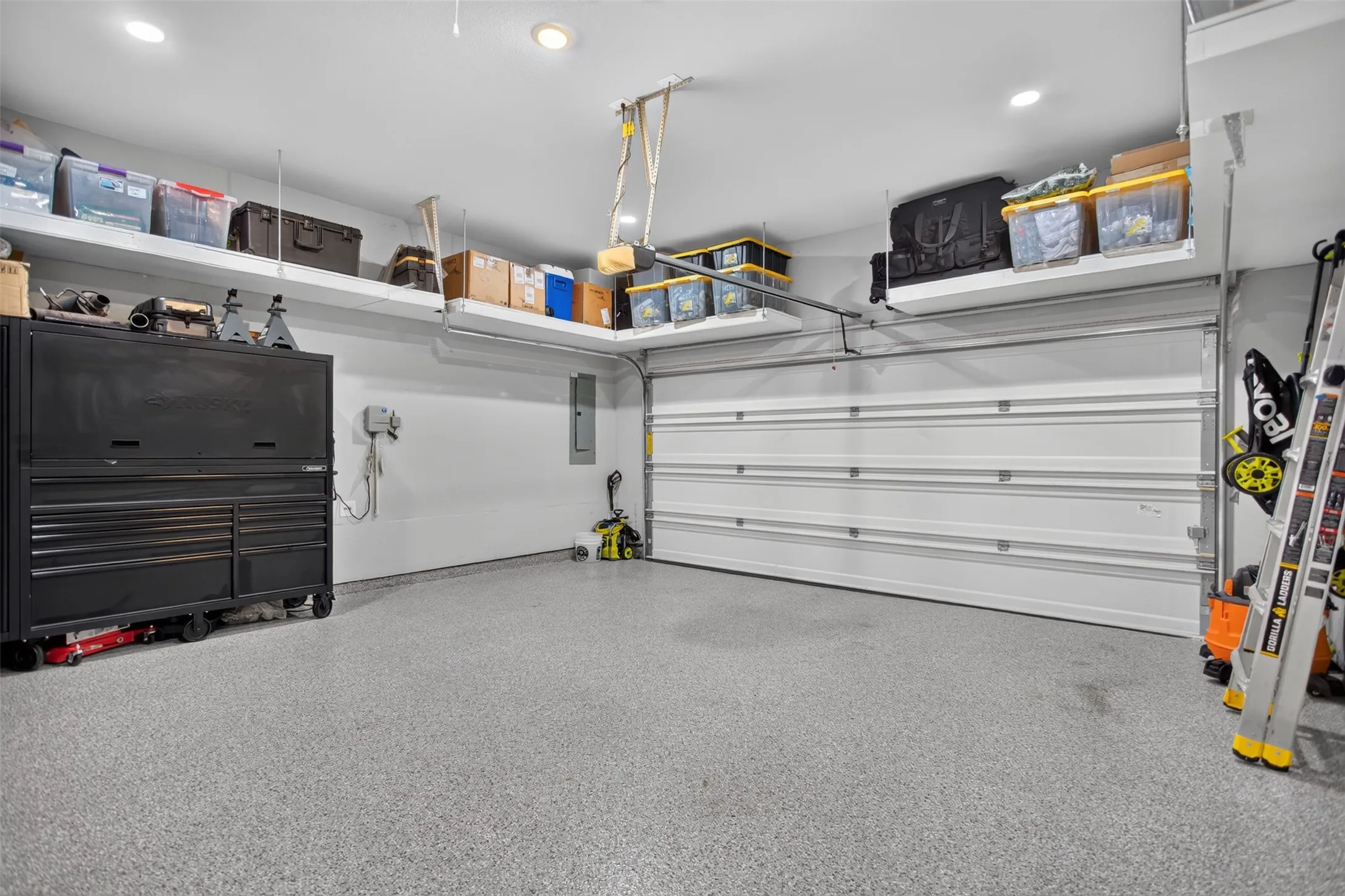 Garage featuring an epoxy-coated floor, overhead shelving, recessed lighting, and an automatic garage door opener