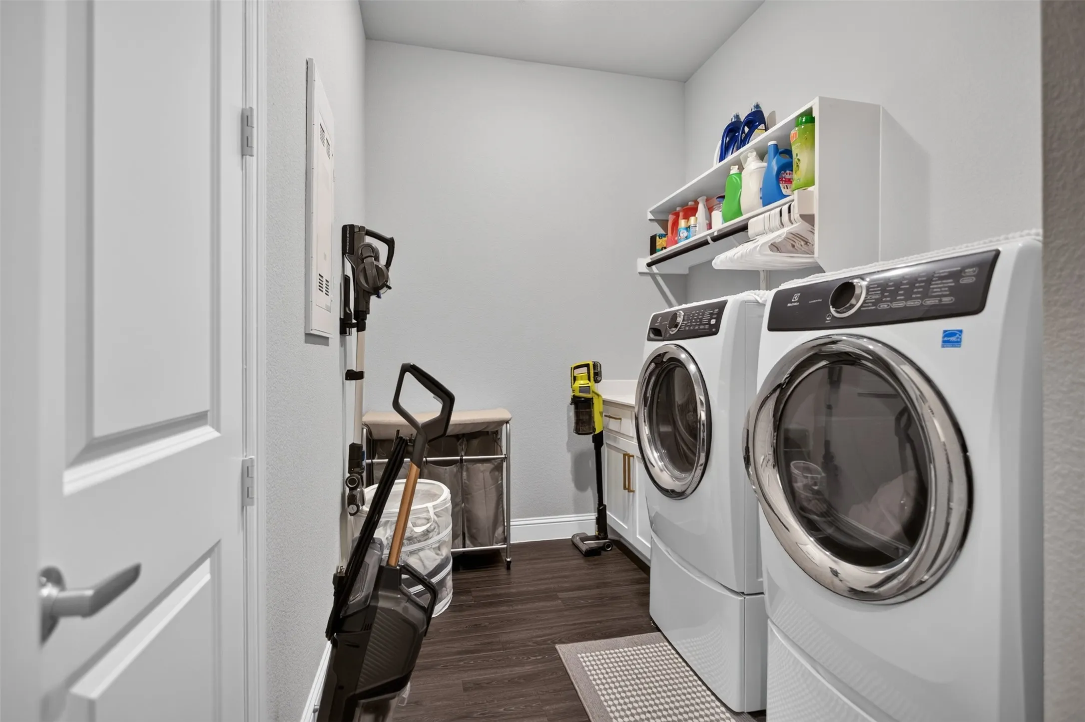 Laundry area featuring dark wood-finish flooring, white built-in shelving, and a built-in countertop