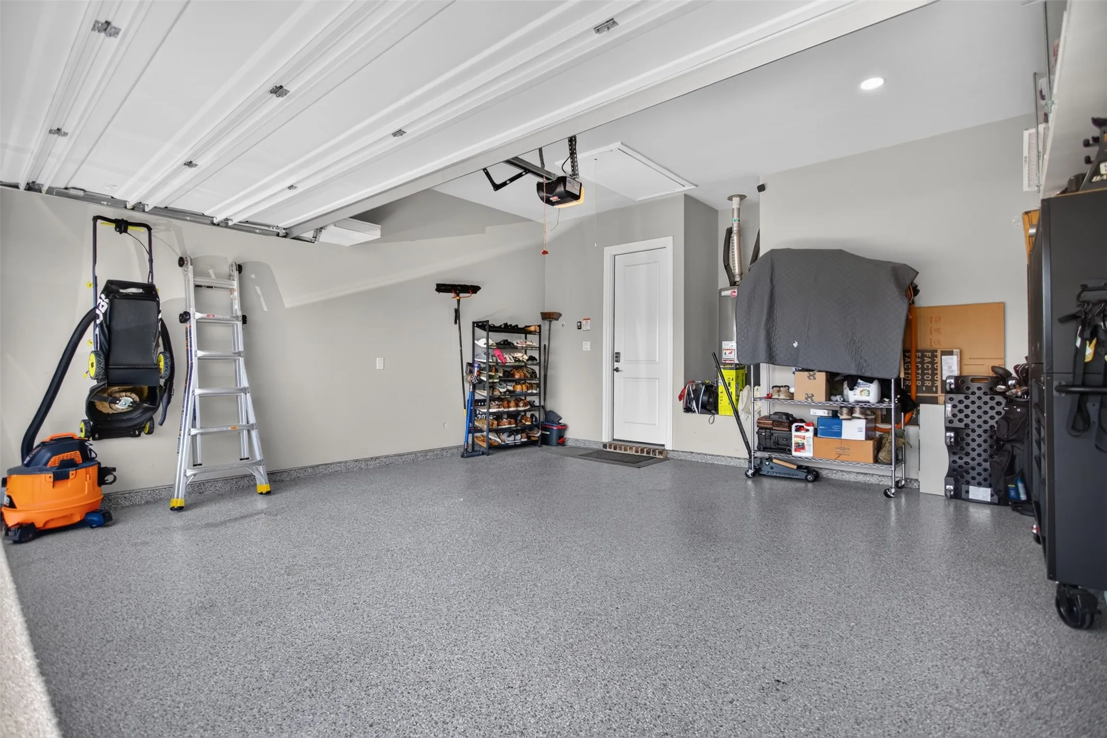 Attached garage with speckled epoxy flooring, white paneled garage door, and recessed lighting
