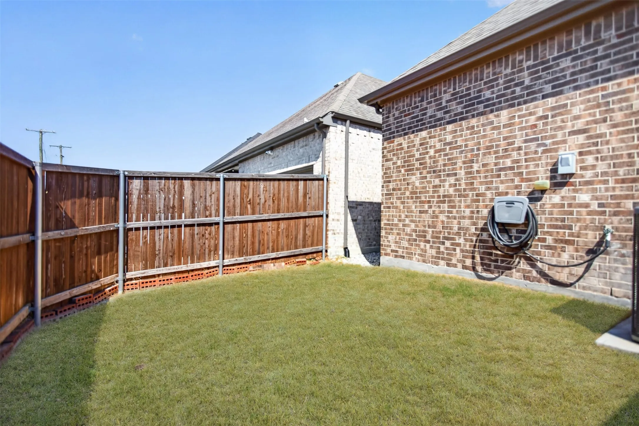 Expansive grassy yard with wood fencing and a brick exterior