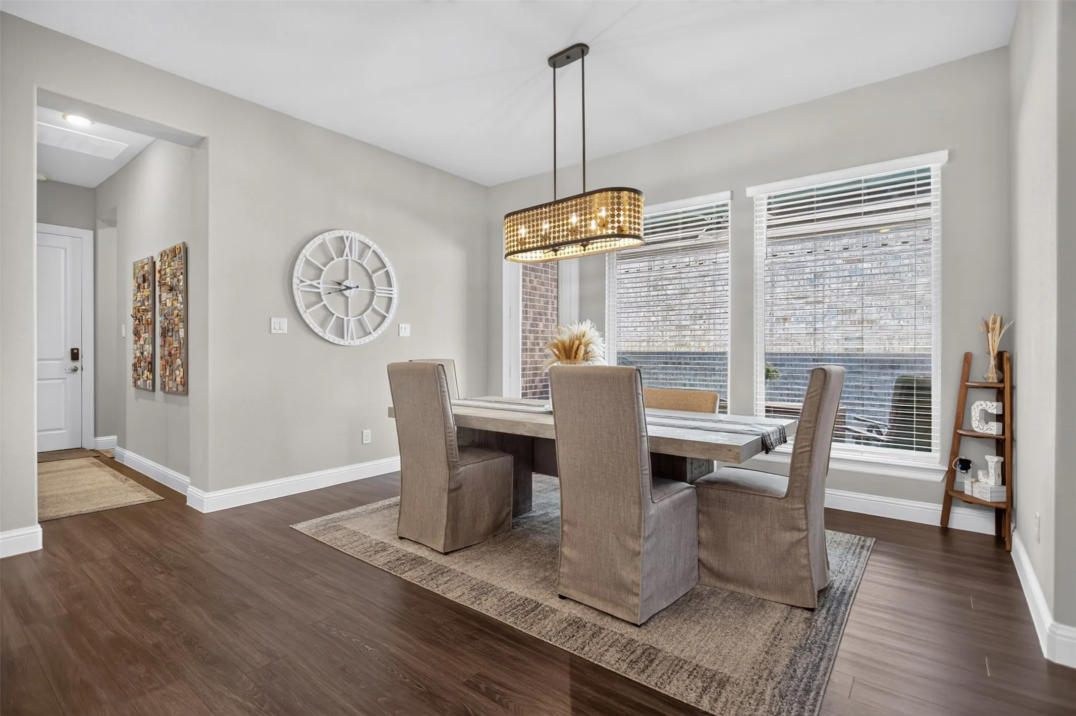 Wood-finish flooring throughout, light gray wall tones, and three large windows with blinds