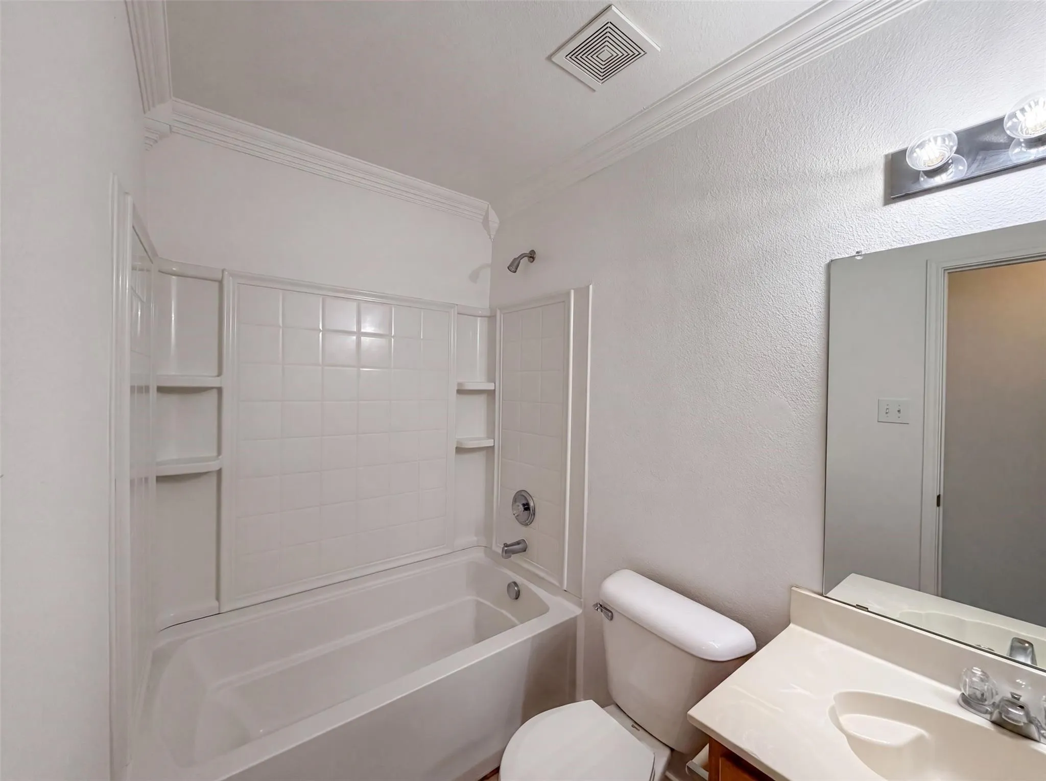 Full bathroom featuring a tub-shower combination with tile surround, a single vanity with an integrated sink, a wall-mounted mirror, and crown molding