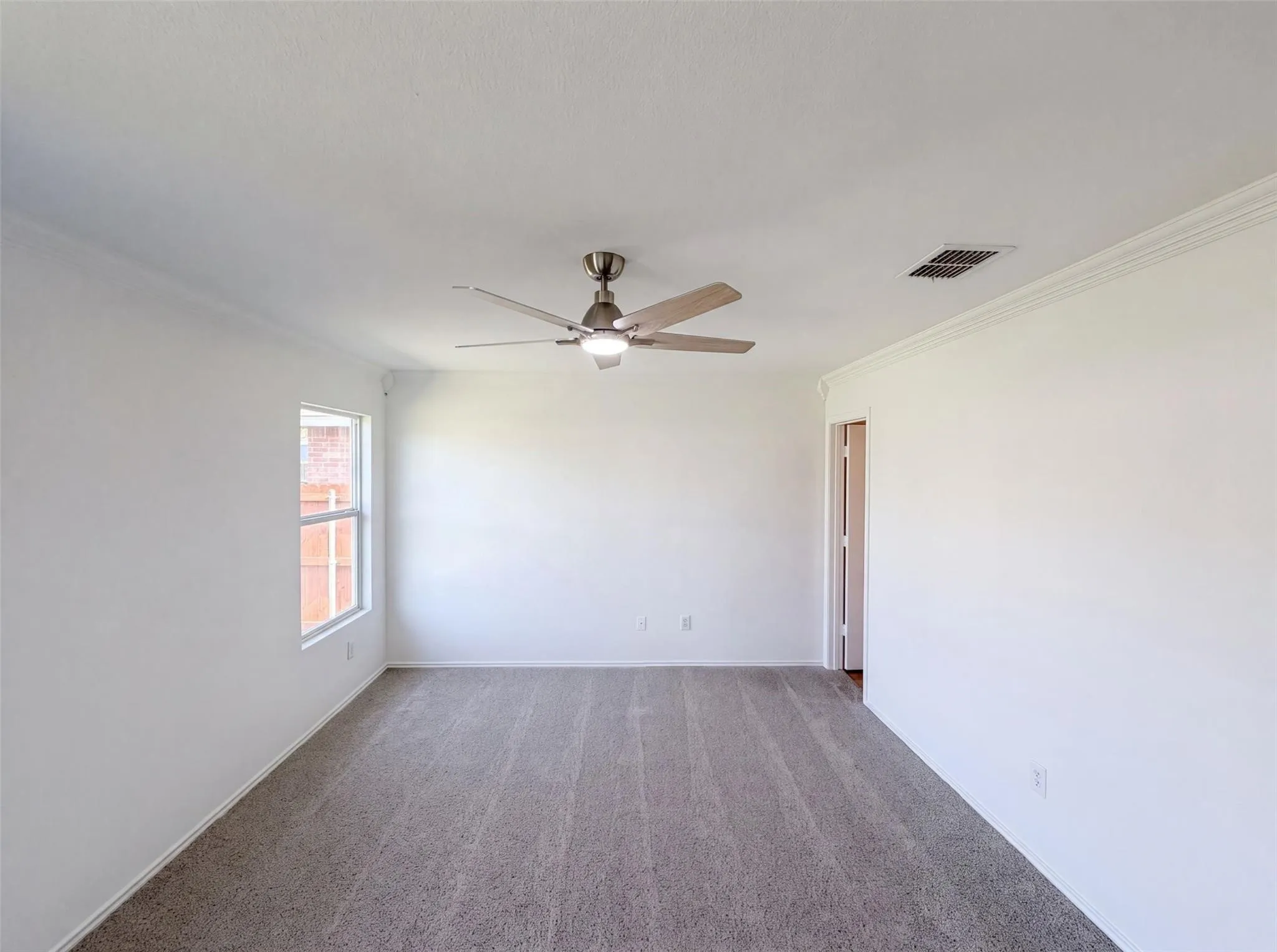 Neutral tone carpeting, white painted walls, and crown molding