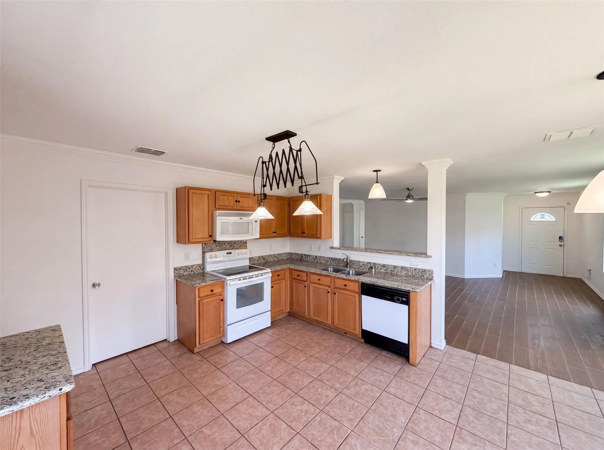Kitchen featuring wood cabinetry, stone countertops, a tile floor, and white appliances including a built-in microwave and range