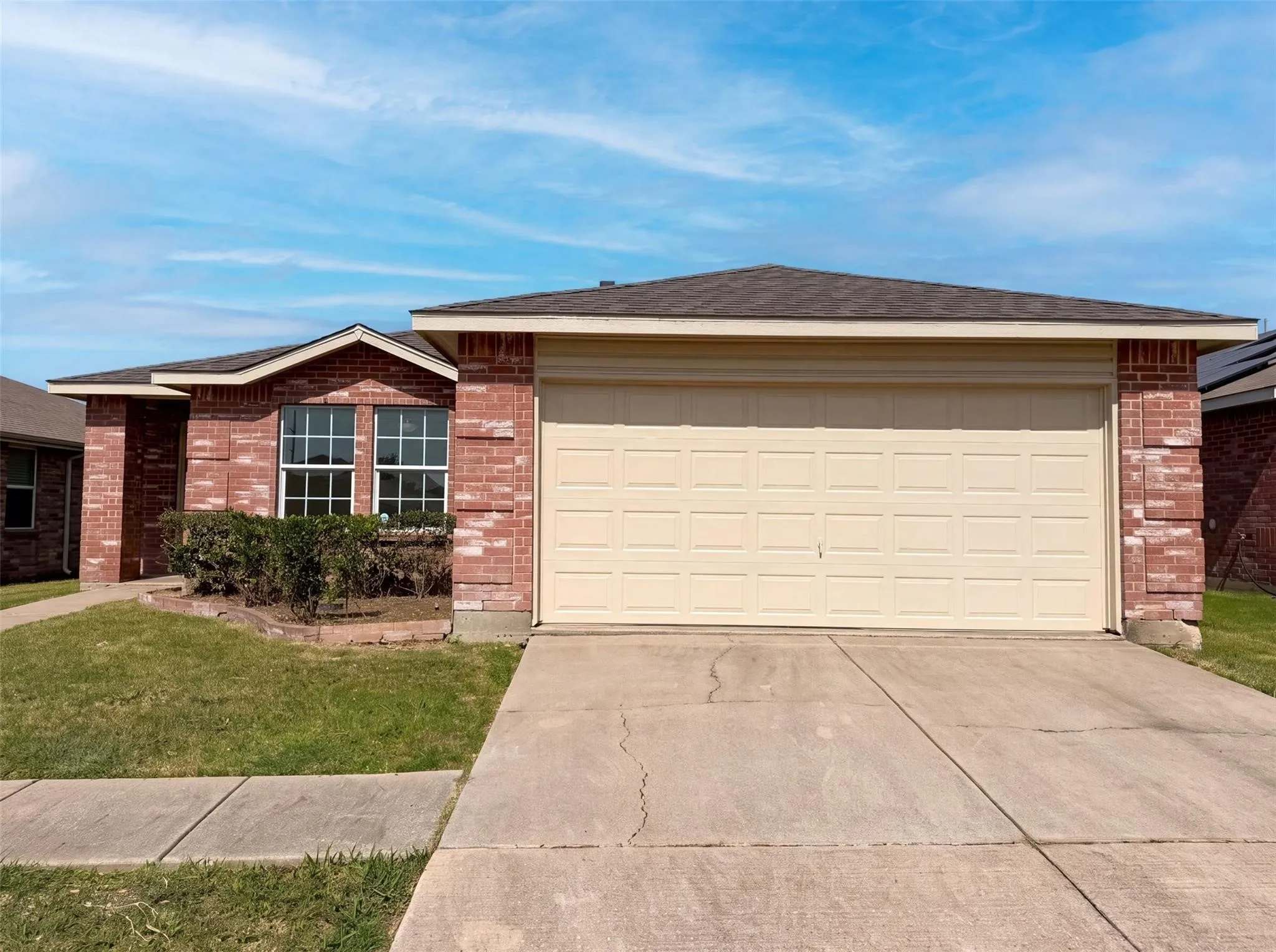 Brick exterior with a gabled entry, attached two-car garage, concrete driveway, and front landscaping