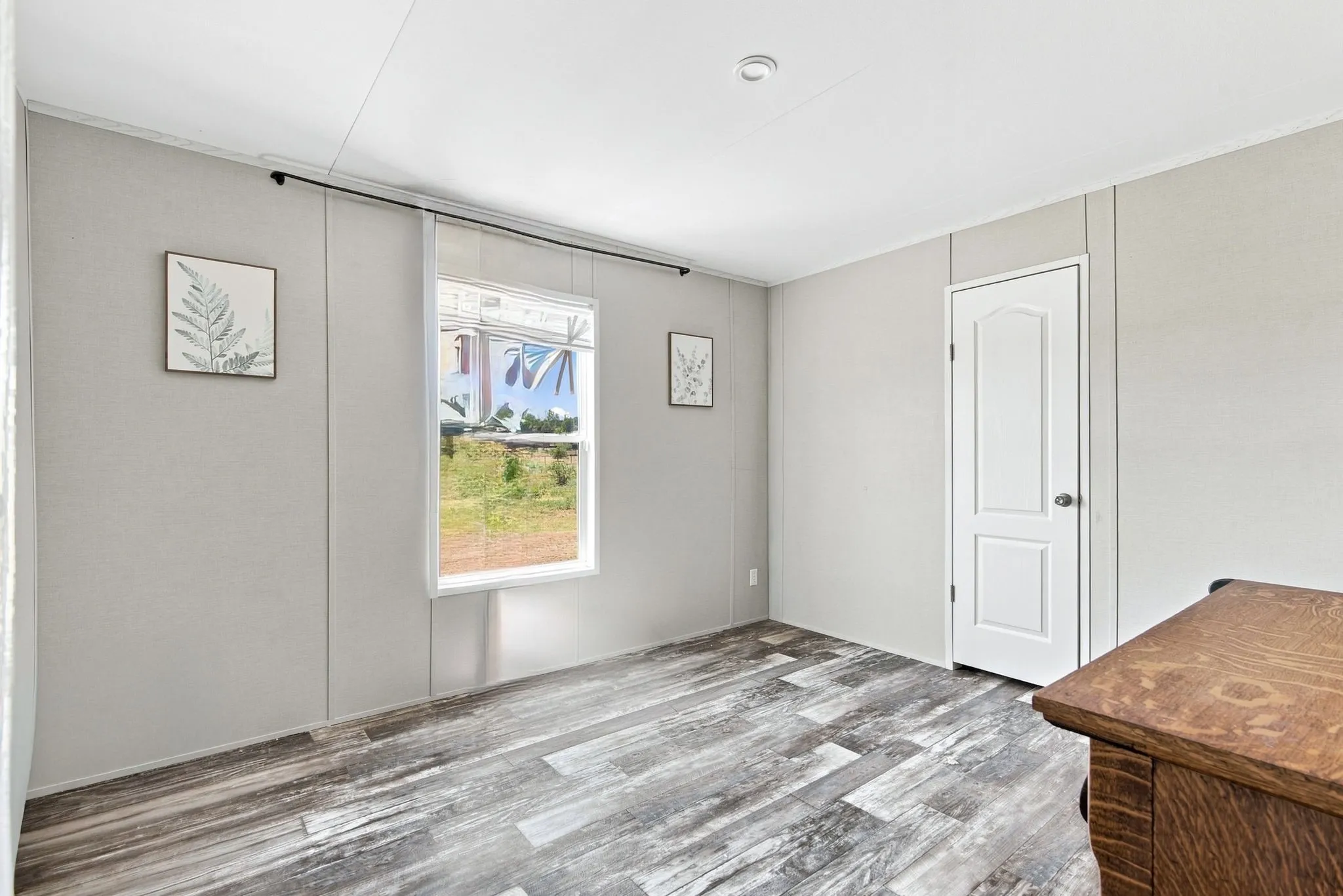 Wood-finish flooring with a white paneled door and recessed ceiling lighting