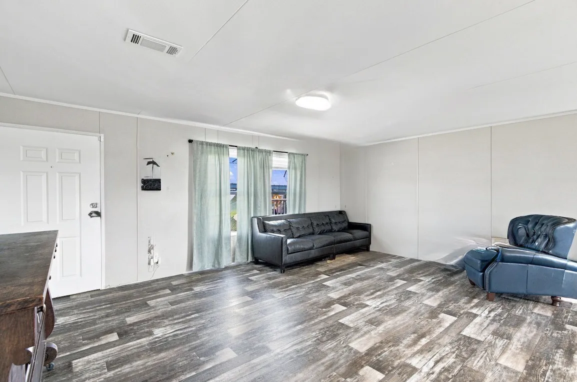 Wood-finish flooring throughout, white paneled walls, and a white entry door with privacy glass