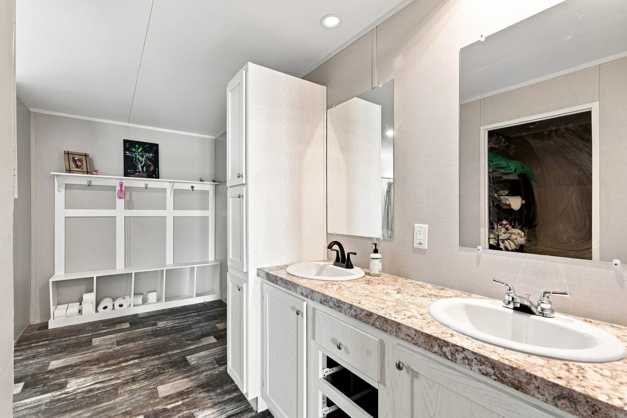 Dual vanity with individual sinks, integrated storage cabinetry, and wood-finish flooring