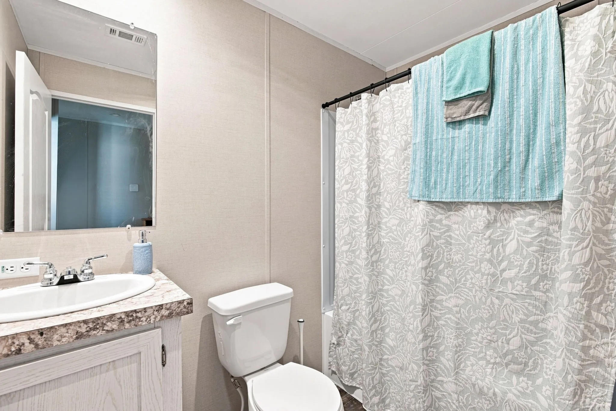 Bathroom featuring a single vanity with an integrated sink, polished chrome faucet, framed mirror, and a full-size toilet