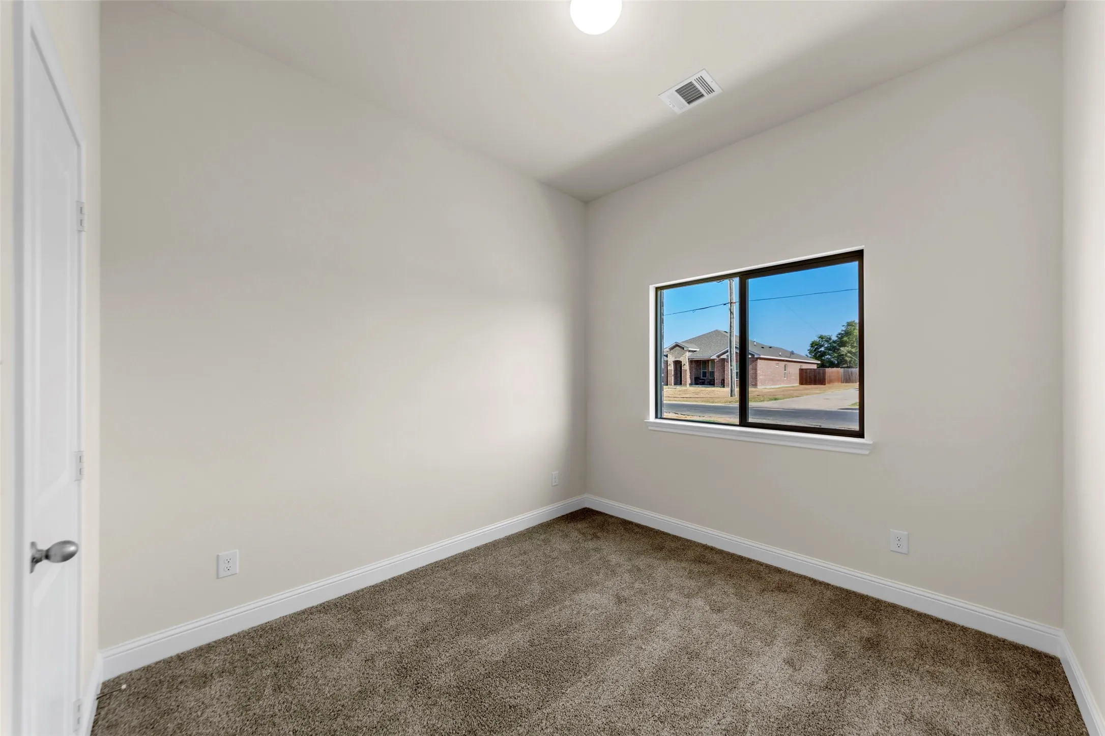 Wall-to-wall carpeting, recessed lighting, double-pane window with black trim, and a white interior door with a brushed nickel knob