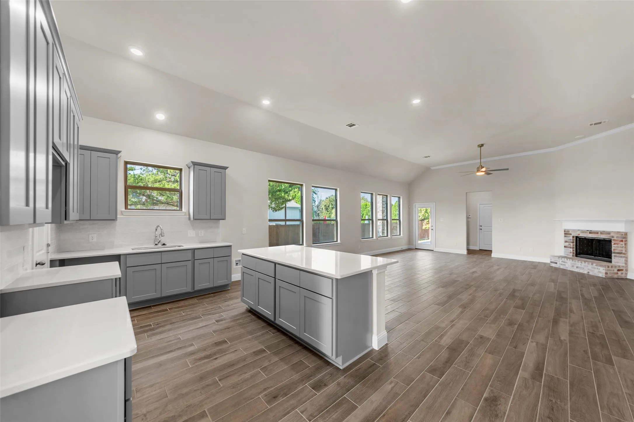 Kitchen featuring gray cabinetry, white countertops, tile backsplash, and a central island