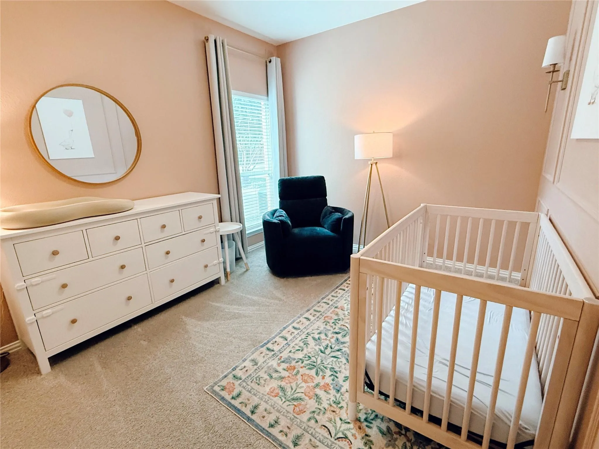 Carpeted room featuring a window with blinds, wall sconce lighting, and decorative wall paneling