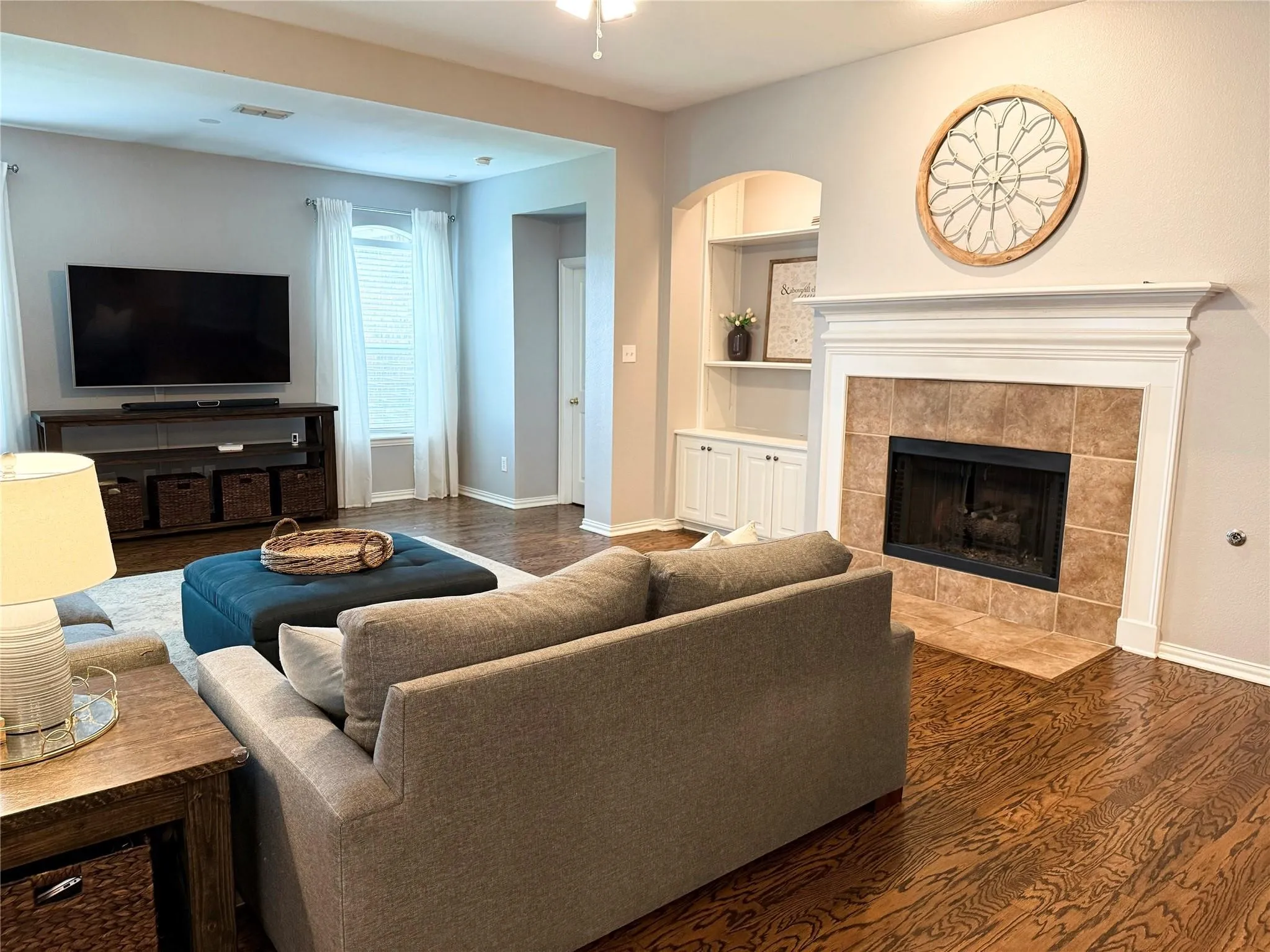 Hardwood flooring throughout, a fireplace with a tile surround and substantial mantel, built-in shelving, and recessed lighting