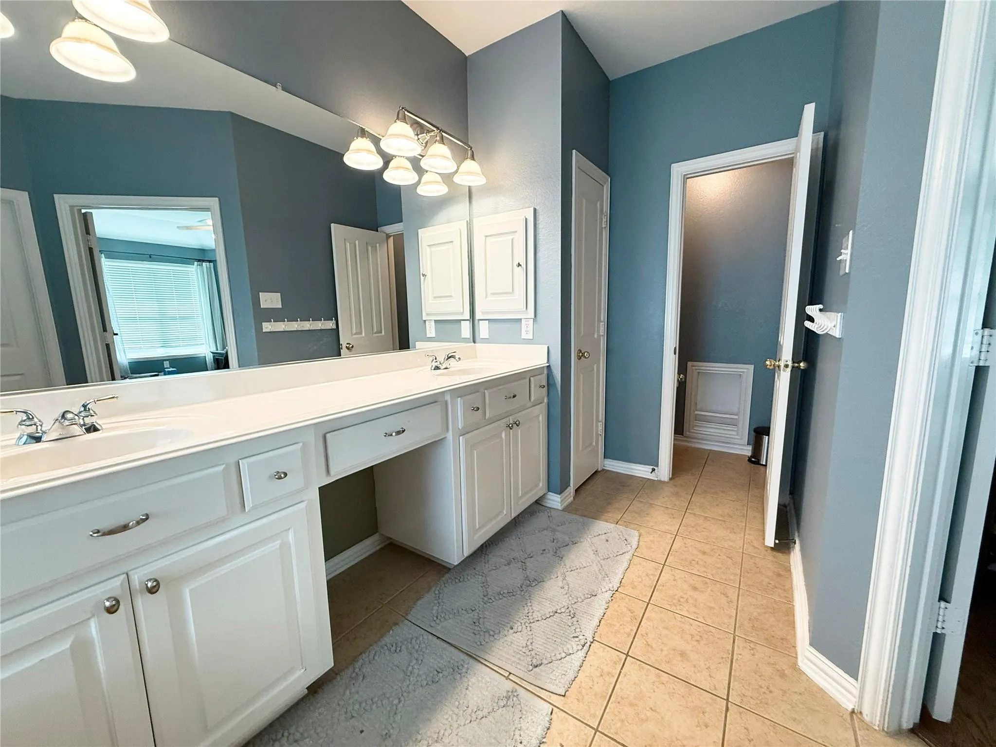 Dual sink vanity with white cabinetry, ample counter space, and integrated storage