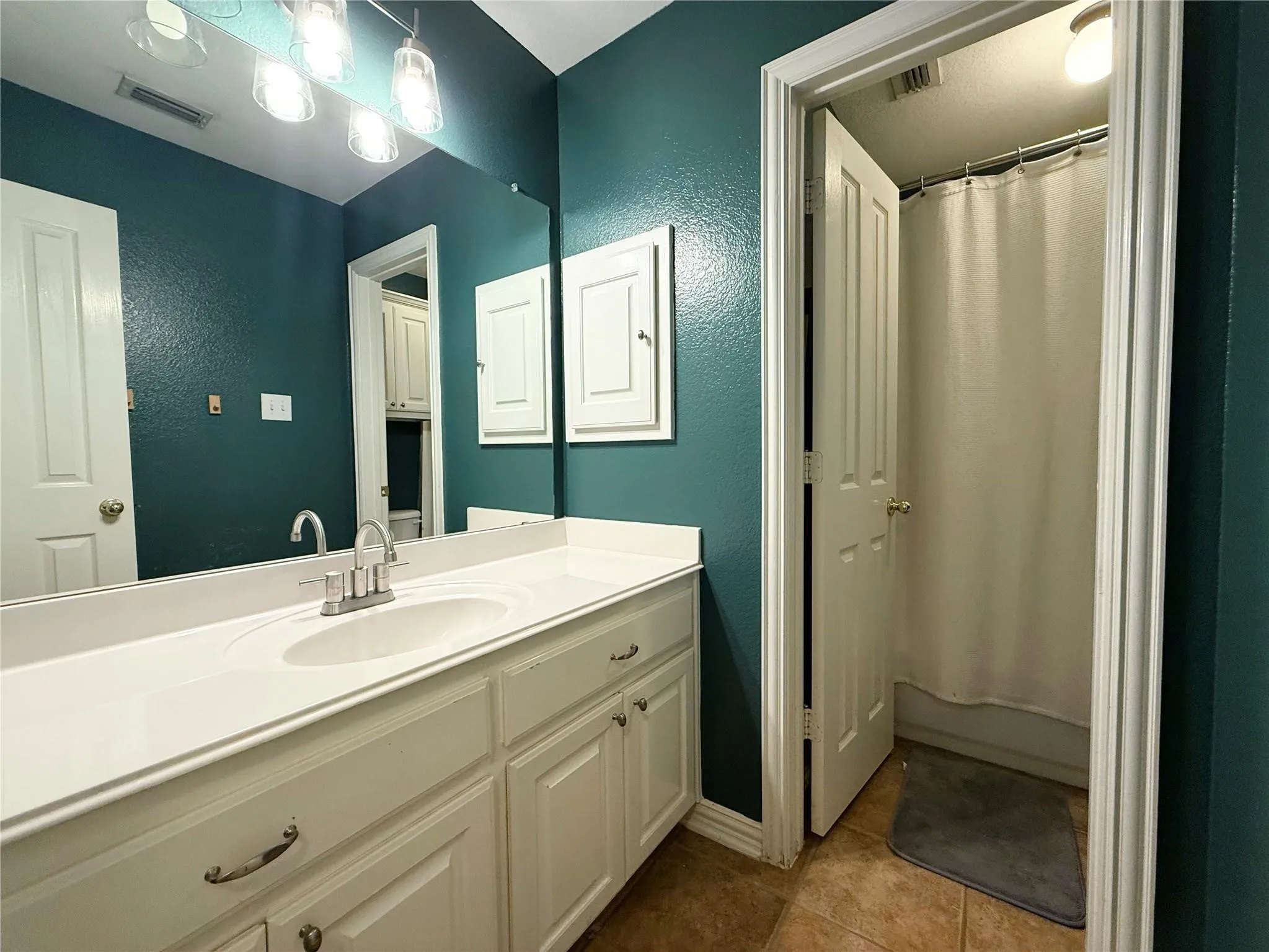 Extended single vanity with an integrated sink, brushed nickel faucet, and under-cabinet storage