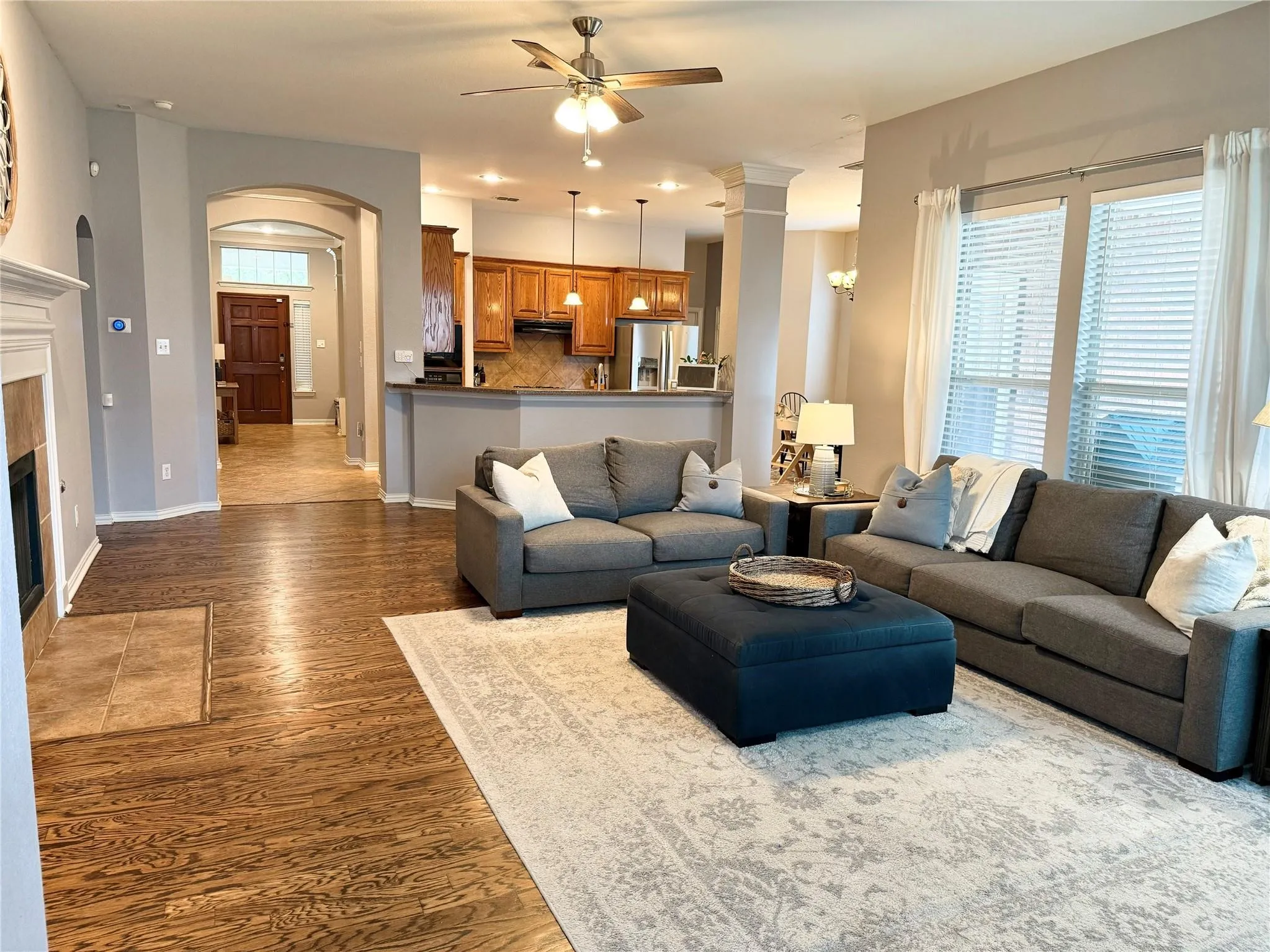 Open-concept living area with wood-finish flooring, a ceiling fan, and large windows