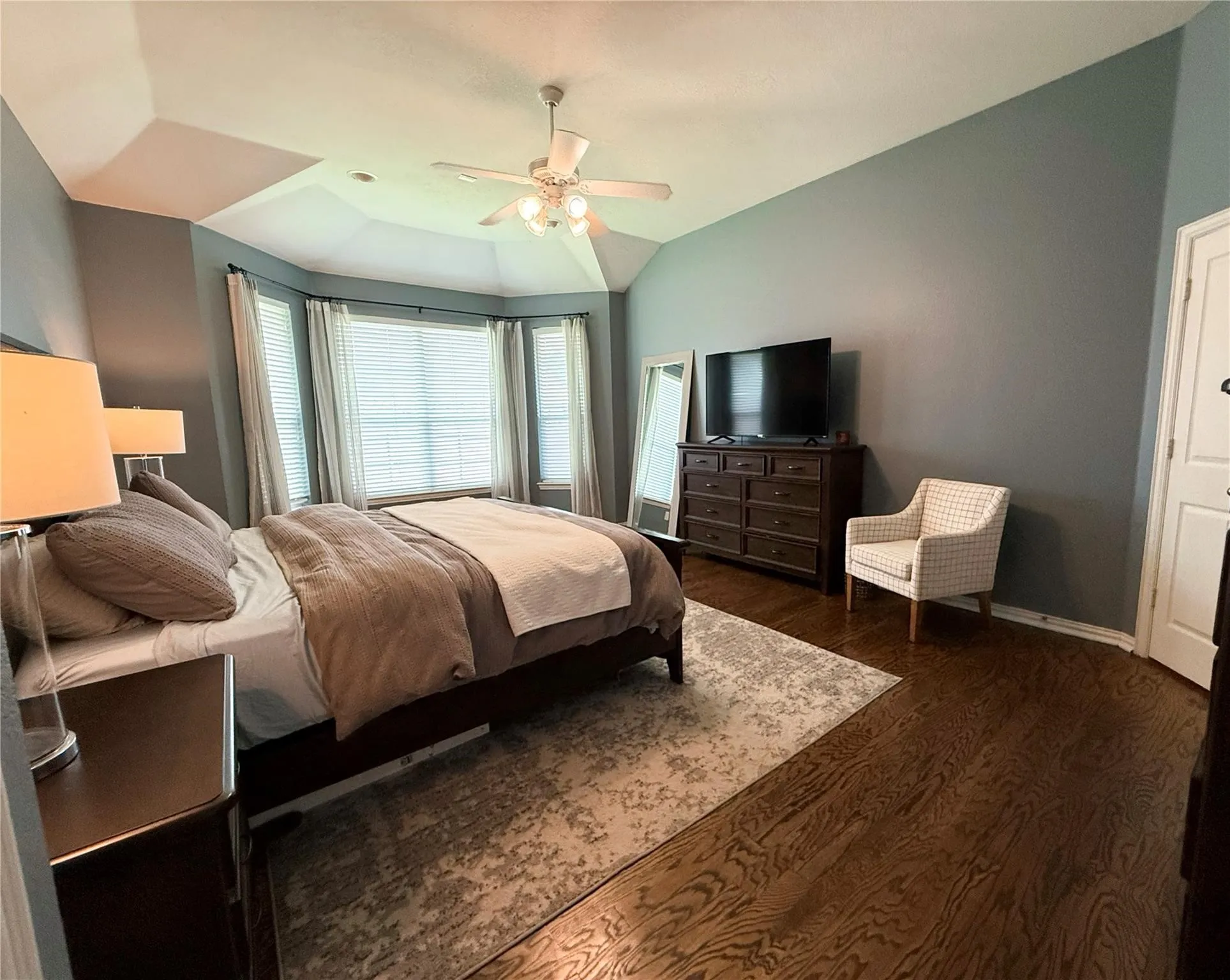 Hardwood flooring, tray ceiling, bay window, ceiling fan, and recessed lighting