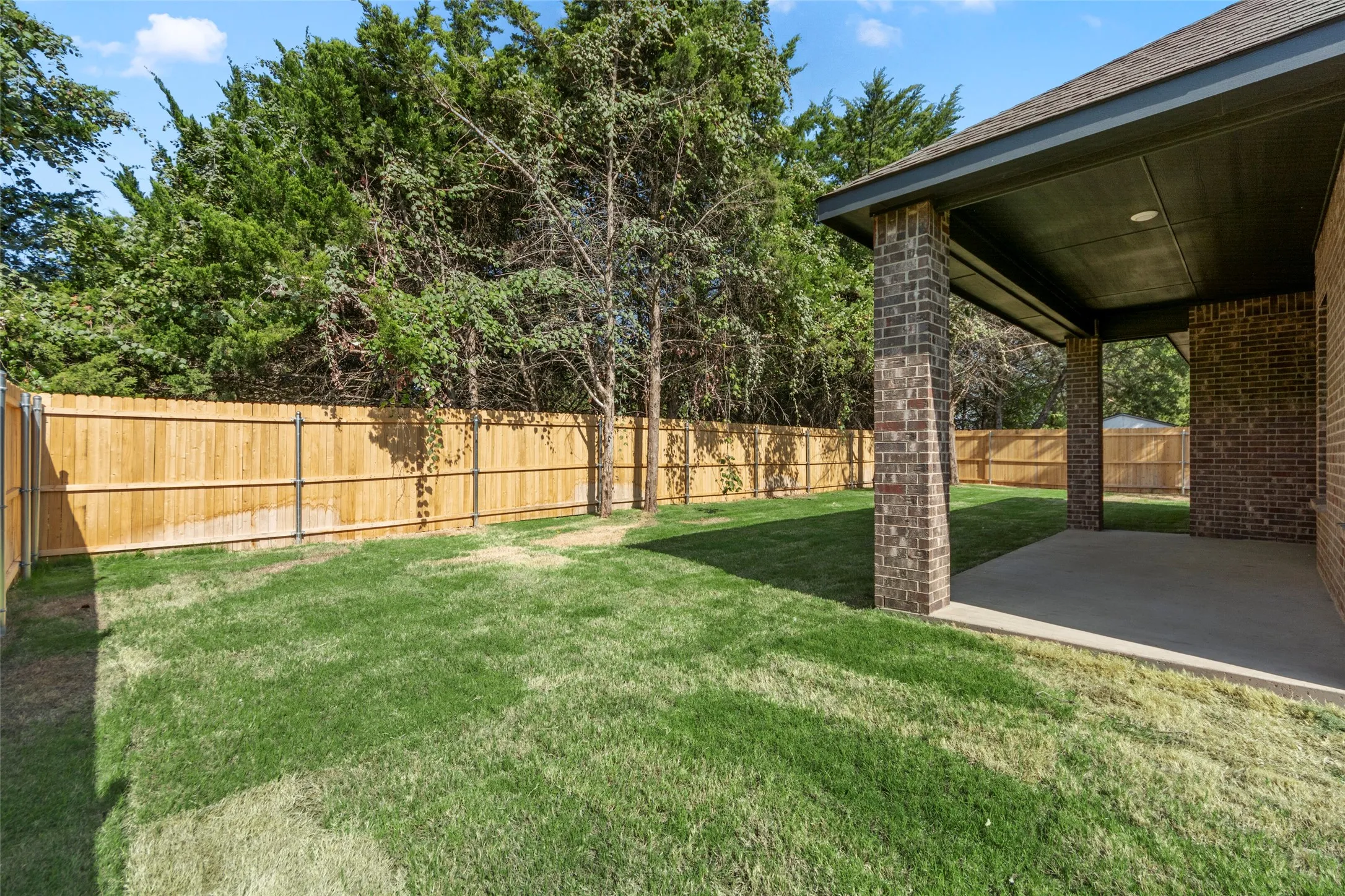 Expansive grassy yard with wood fencing and mature trees