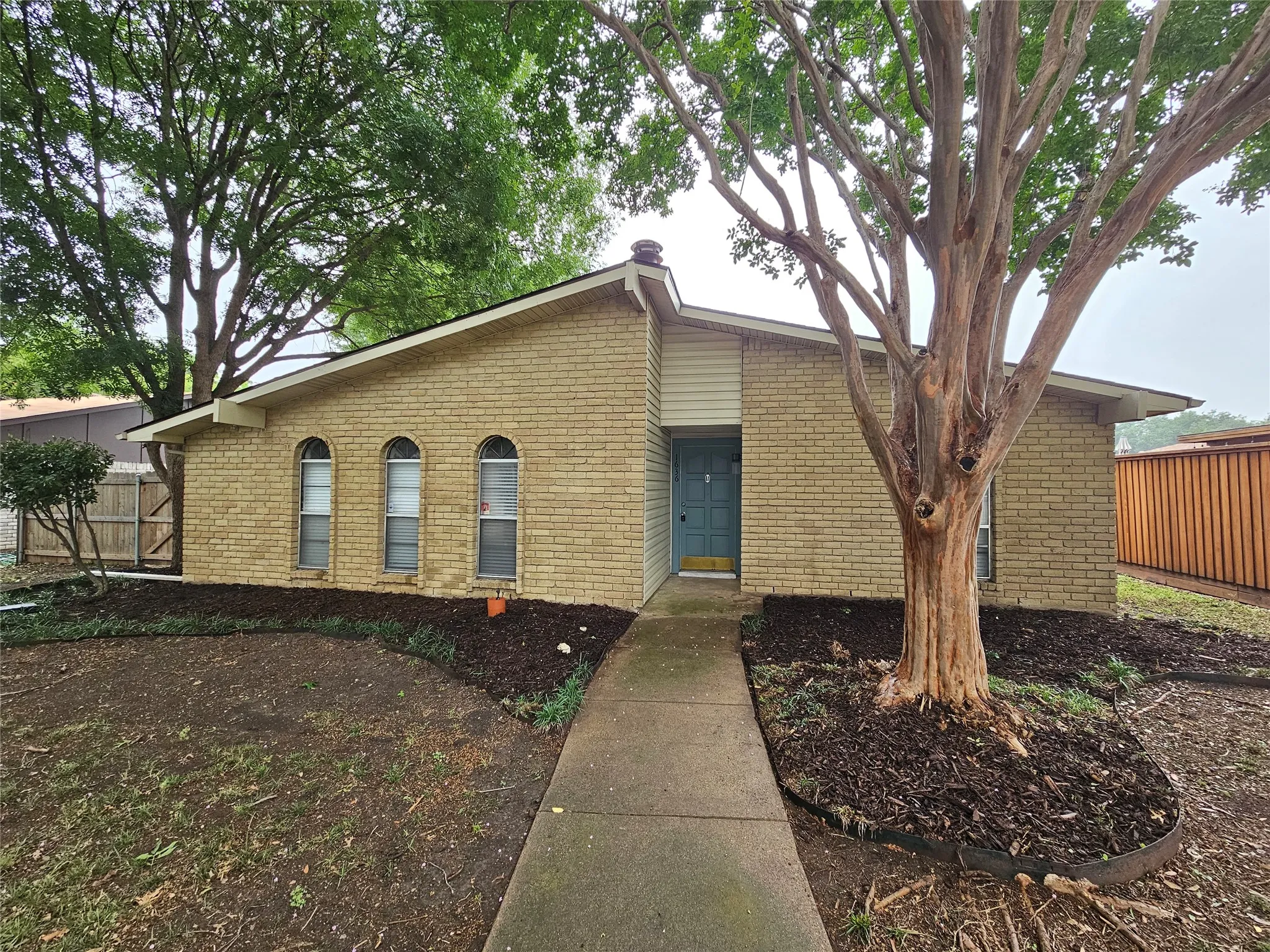 Brick exterior with a light blue entry door, featuring three arched windows