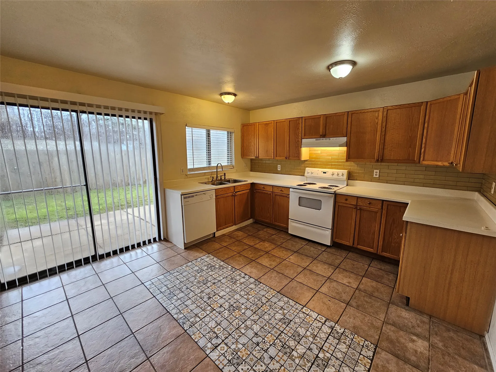 Kitchen featuring wood cabinetry, solid surface countertops, tile flooring, and a tile backsplash