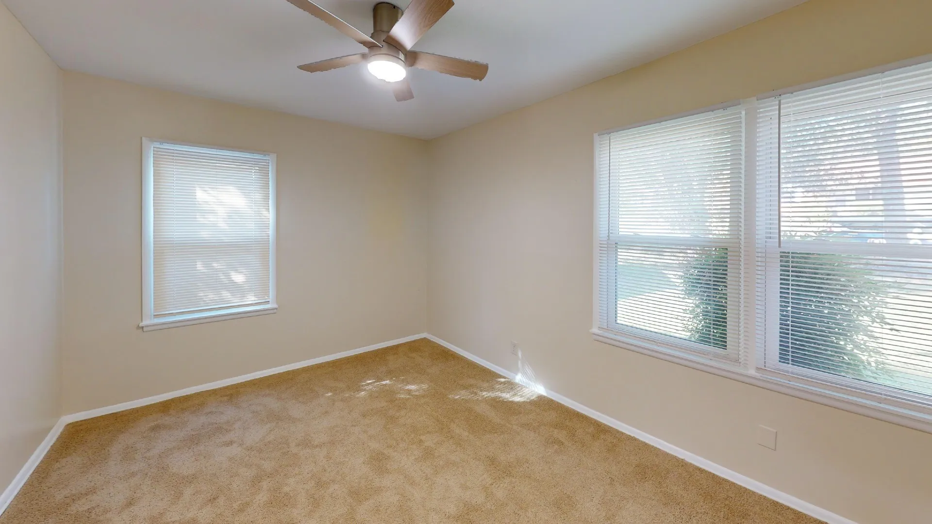 Carpeted room featuring multiple windows with blinds and a ceiling fan with integrated lighting