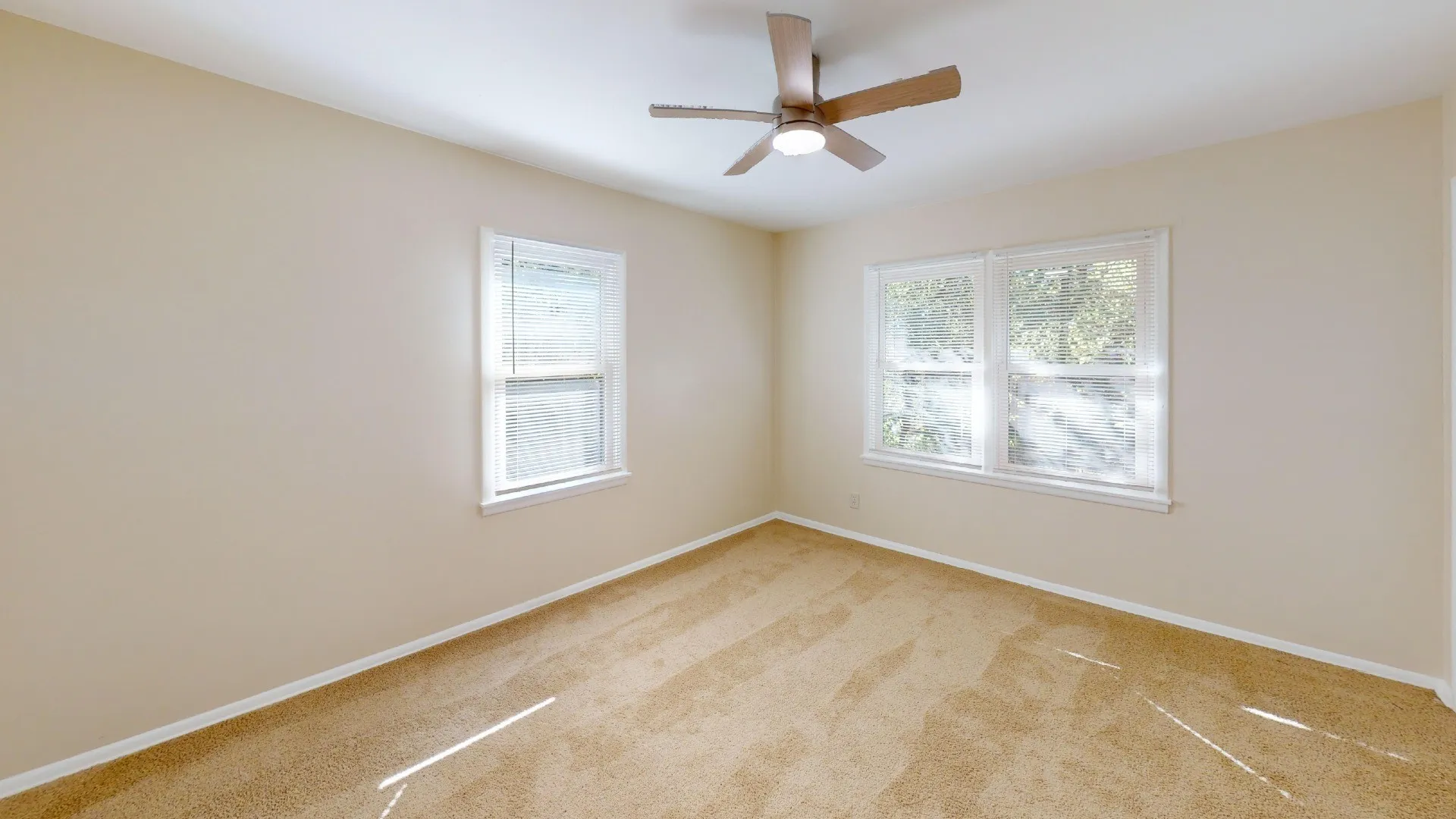 Neutral-toned walls, plush carpet flooring, and a ceiling fan with integrated lighting