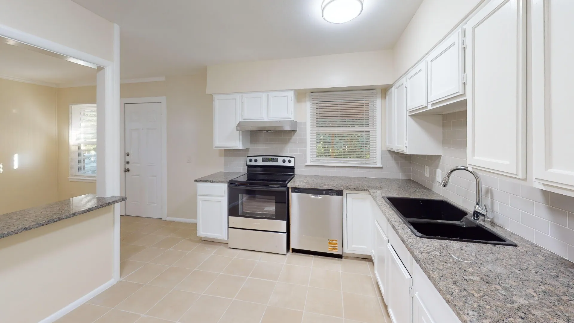 Kitchen featuring white cabinetry, stone-finish countertops, subway tile backsplash, stainless steel appliances, and tile flooring