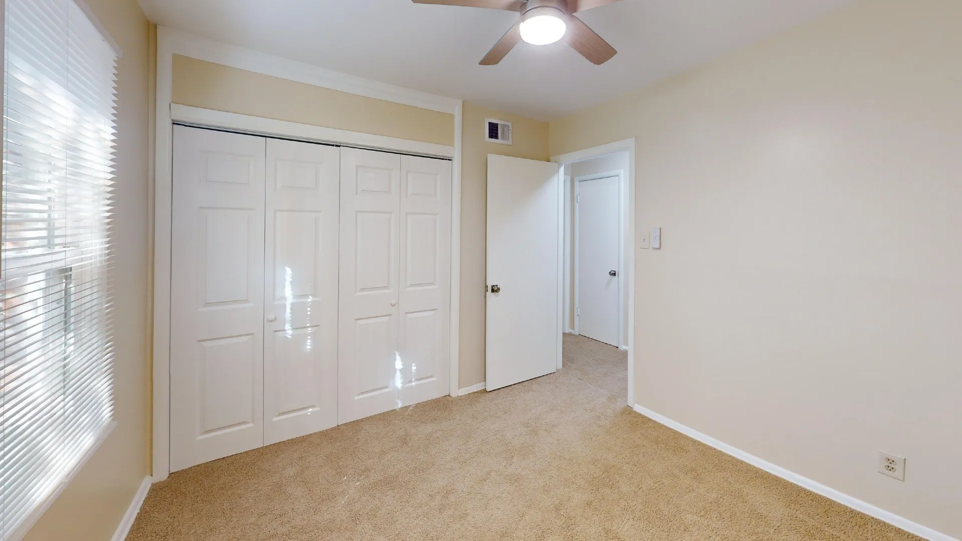 Plush carpeting, paneled bi-fold closet doors, crown molding, window with horizontal blinds, and a ceiling fan with integrated lighting