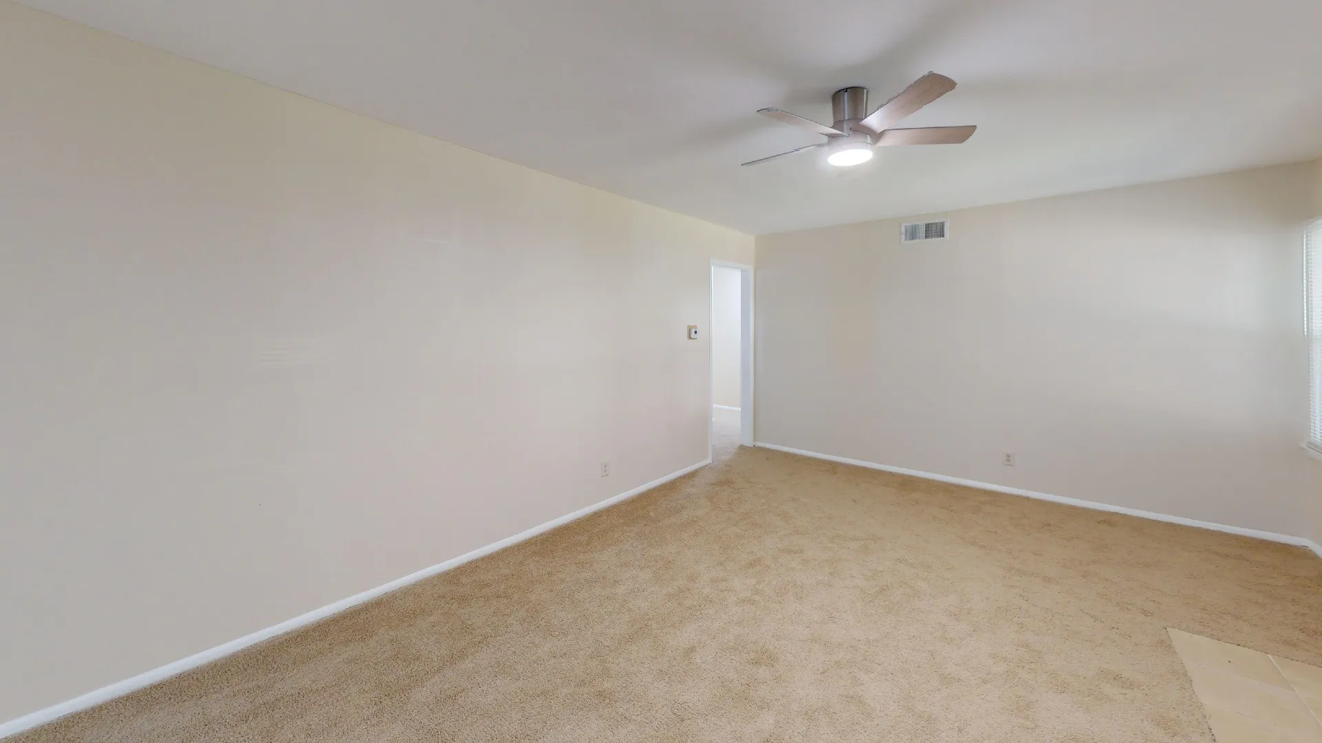 Wall-to-wall carpeting with light-toned walls and a ceiling fan with integrated lighting