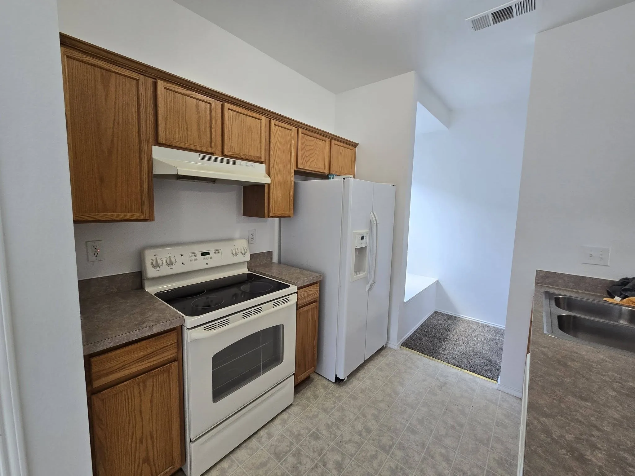 Kitchen featuring wood cabinetry, laminate countertops, a white electric range, a white refrigerator , and a double basin stainless steel sink