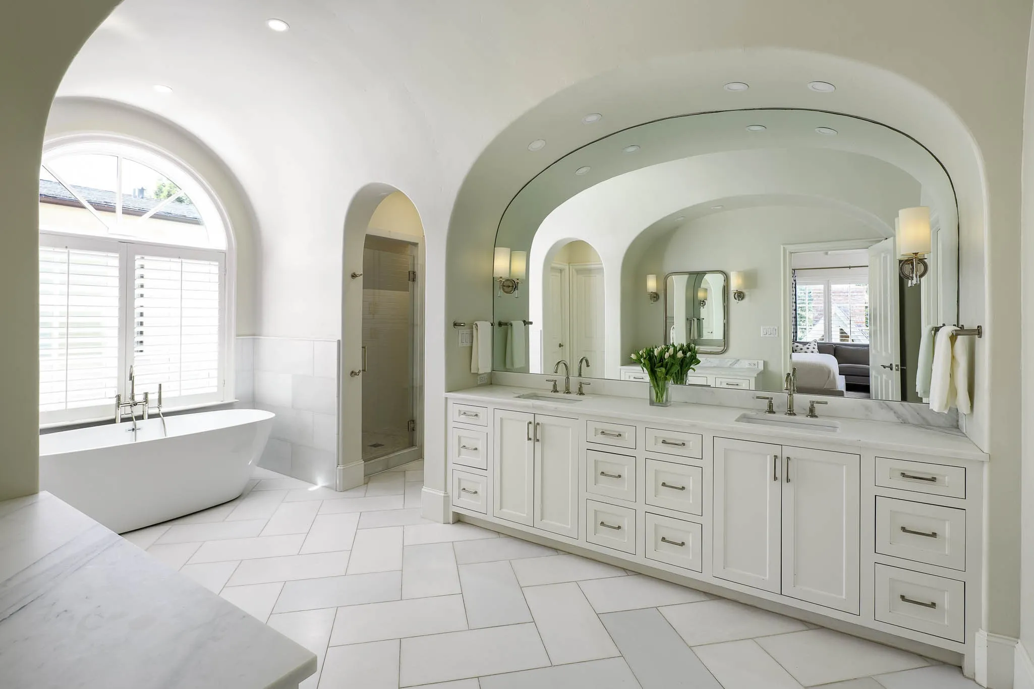 Primary bathroom with dual vanities, stand alone tub, and dual large walk-in closets