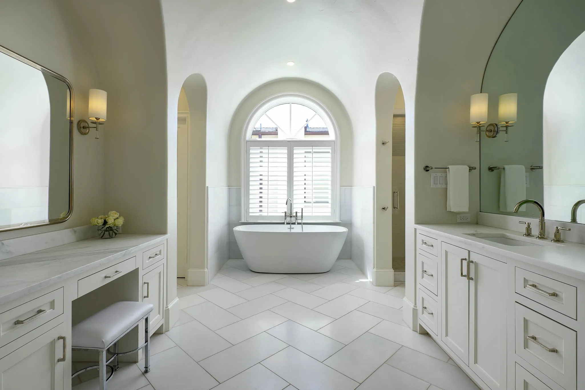 Primary bathroom with dual vanities, stand alone tub, and dual large walk-in closets