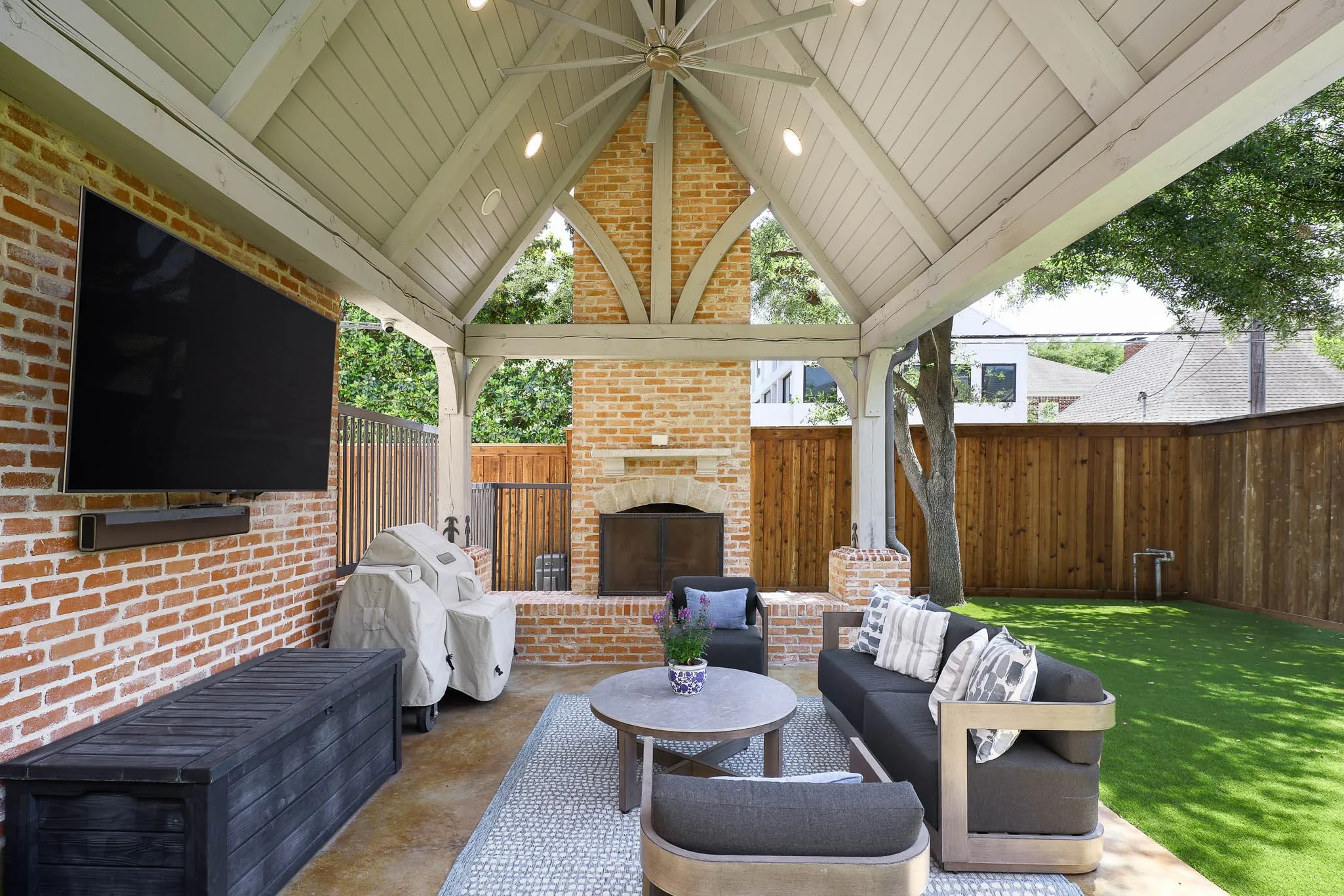 Outdoor covered loggia with wood beamed vaulted ceiling and gas fireplace