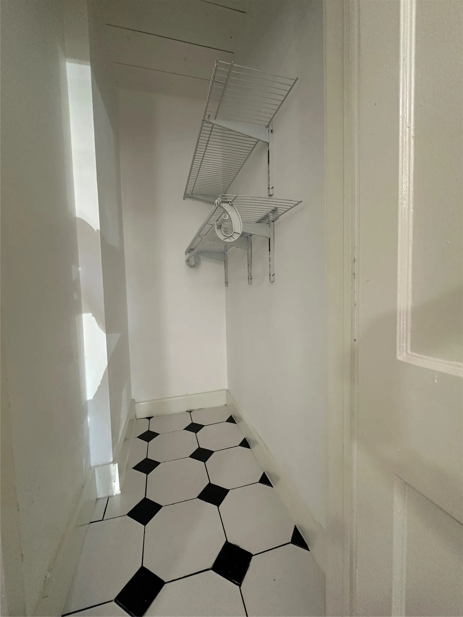 Black and white octagon tile flooring with white wall-mounted shelving