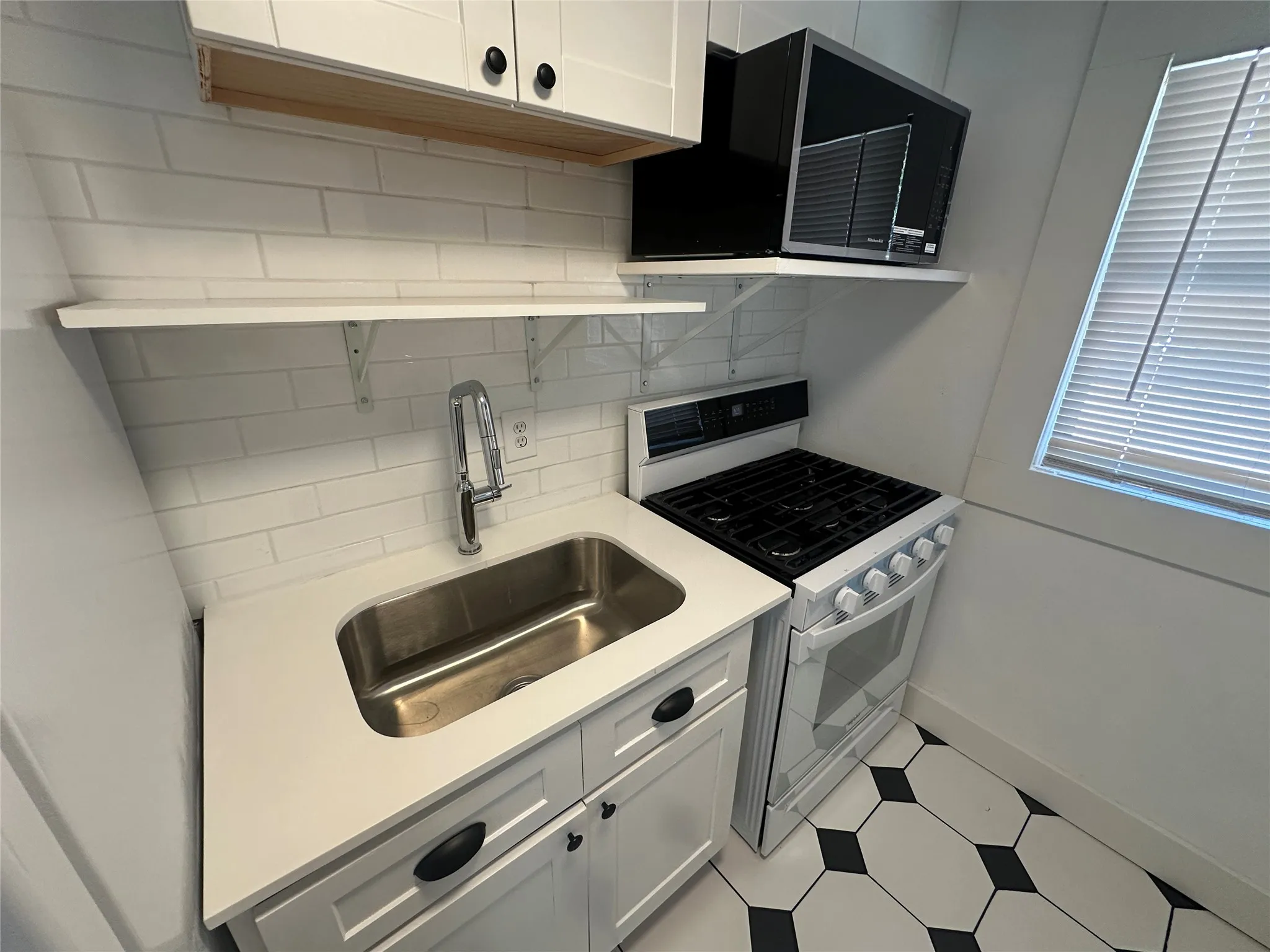 Kitchen featuring white shaker cabinetry, stainless steel sink, white subway tile backsplash, and a gas range