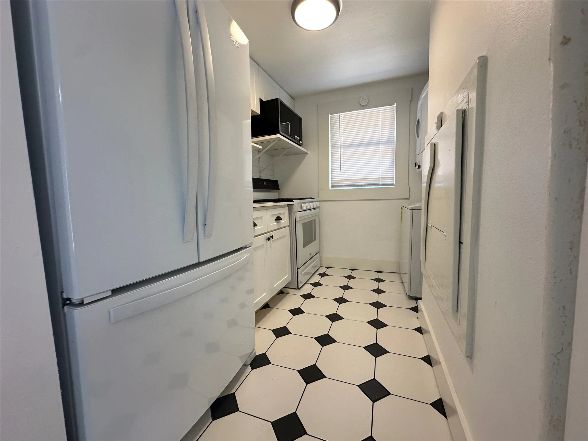 Kitchen featuring a white refrigerator, white oven range, white cabinetry, open shelving, and black and white patterned floor tiles