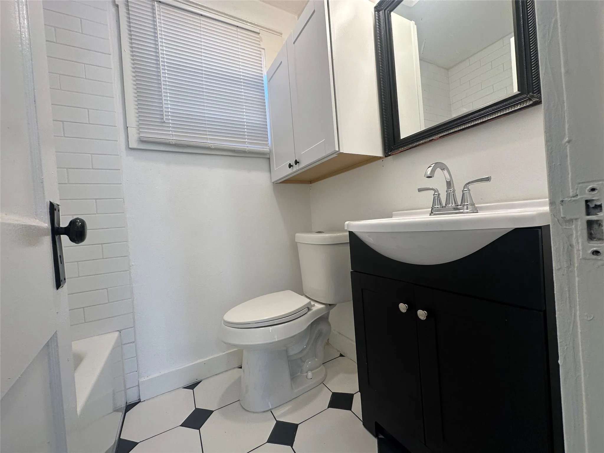 Bathroom featuring a single vanity with dark cabinetry, white countertop, and chrome faucet