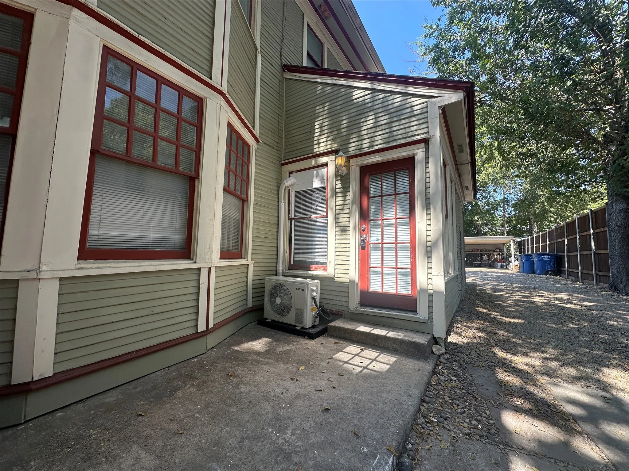 Siding exterior with contrasting trim, bay window, glass-panel door, and a gravel driveway