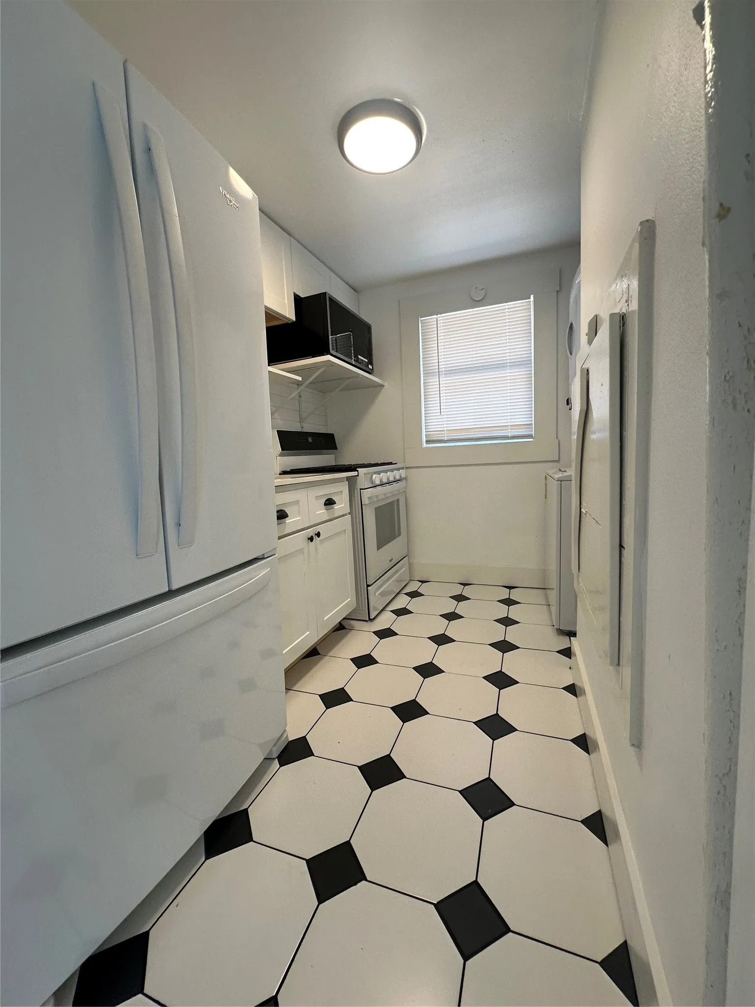 Kitchen featuring white cabinetry, white appliances, a built-in microwave, and a black and white geometric tile floor