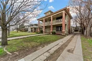 Two-story property featuring a double-level porch with columns, a central cupola, and a concrete driveway