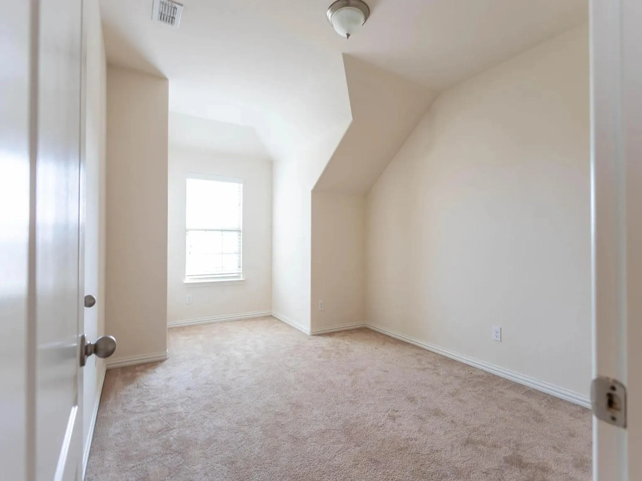 Carpeted room with a window, white trim, and a ceiling-mounted light fixture