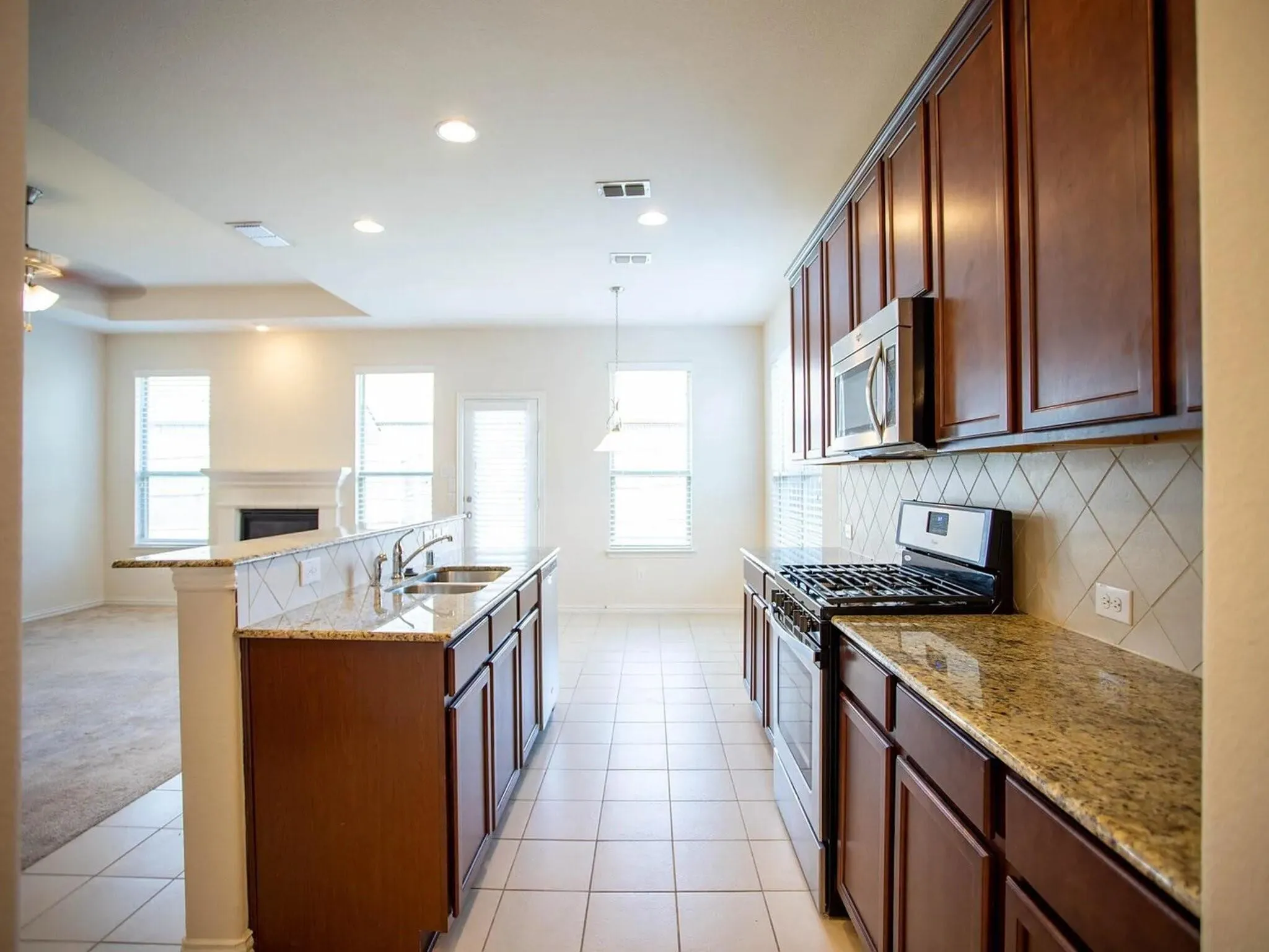 Kitchen featuring wood cabinetry, granite countertops, tile backsplash, stainless steel appliances, and tile flooring